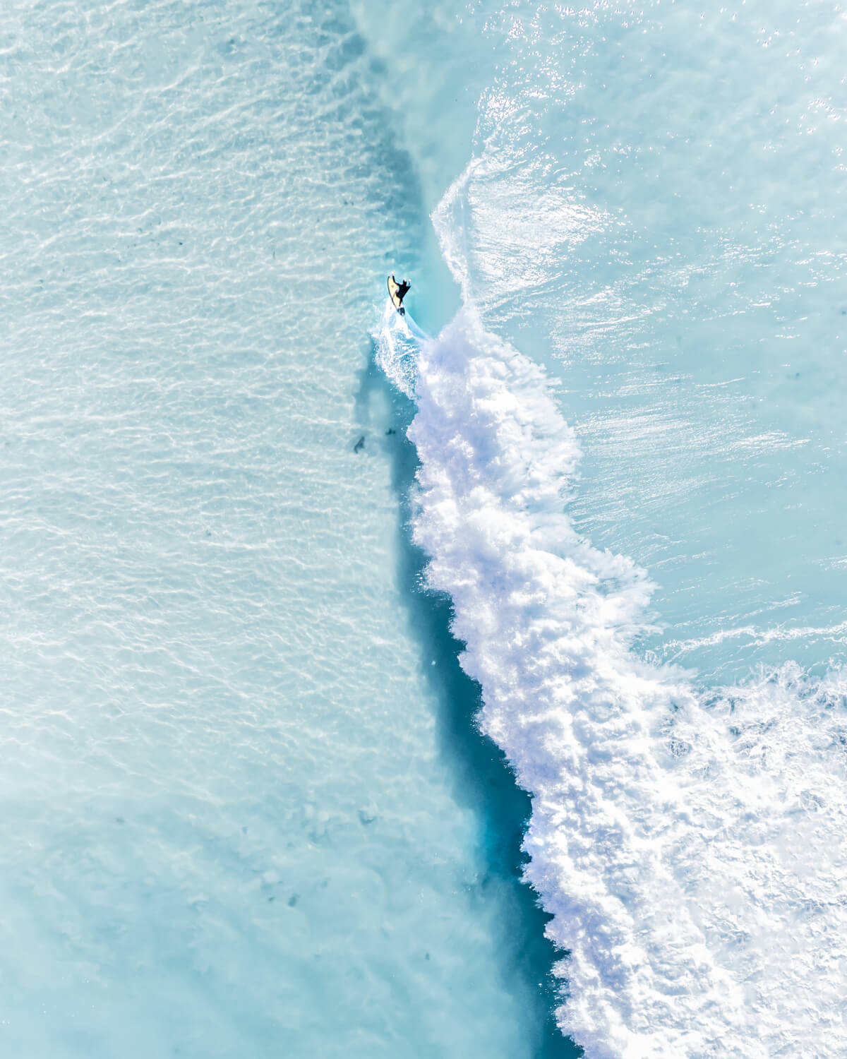 A photo taken from above of a surfer riding a beautiful clean wave