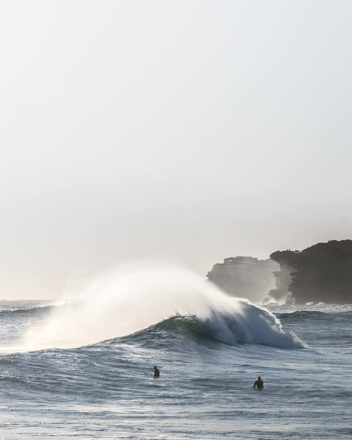 Huge wave crashing on surfers in Bronte Beach on a big swell morning