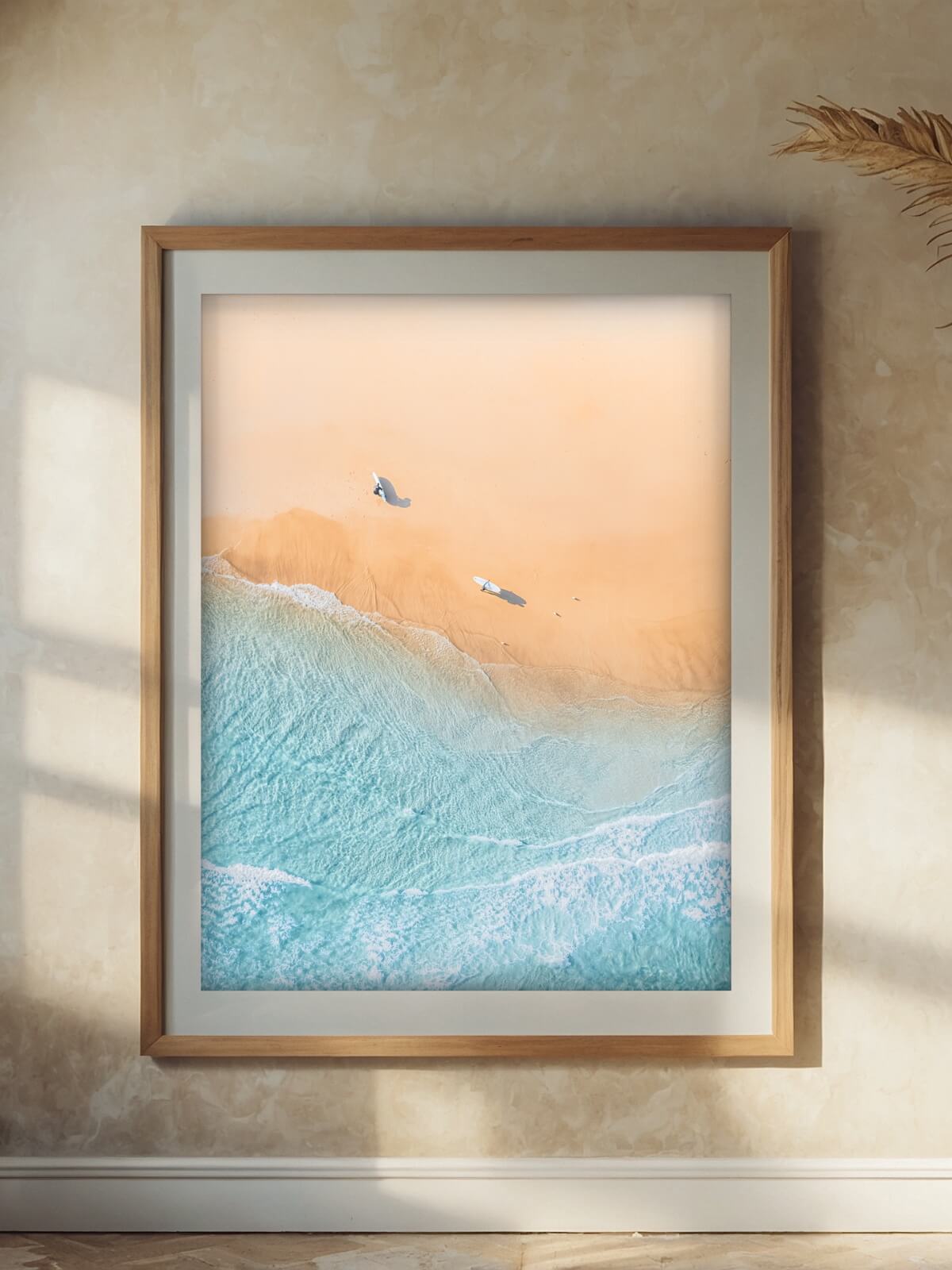 Framed aerial print of The Pass in Byron Bay, displaying surfers on the sandy shore with soft waves in the background.