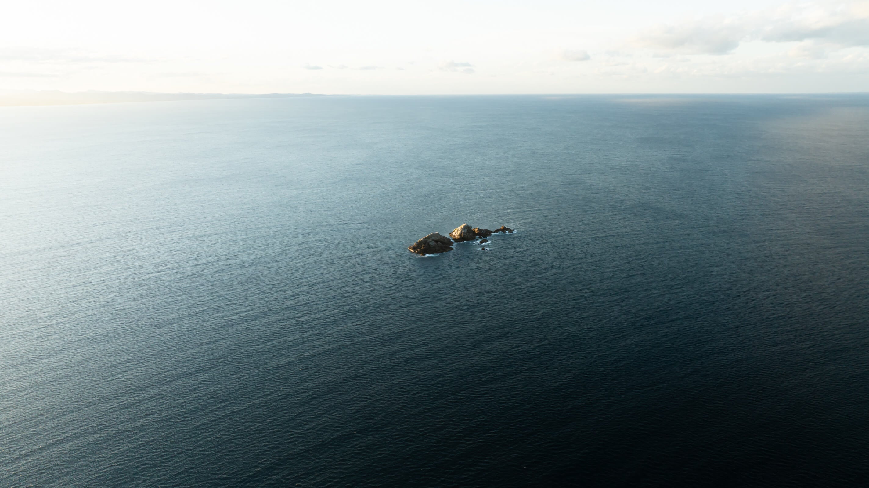 An aerial view of Julian Rocks in Byron Bay, at unset when the light shine bright on from the west.