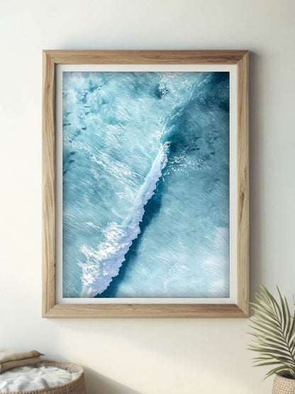 Aerial view of a surfer riding a long ocean wave at Bronte Beach with a minimalist ocean background