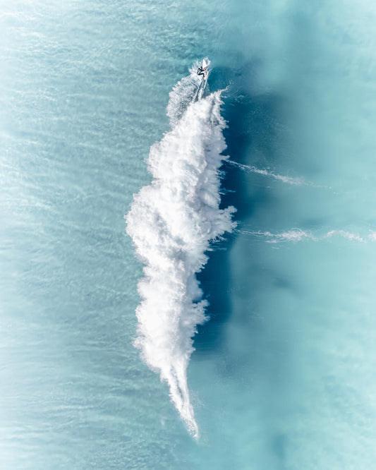 Aerial view of a surfer creating an abstract wake on turquoise waves at Bronte Beach