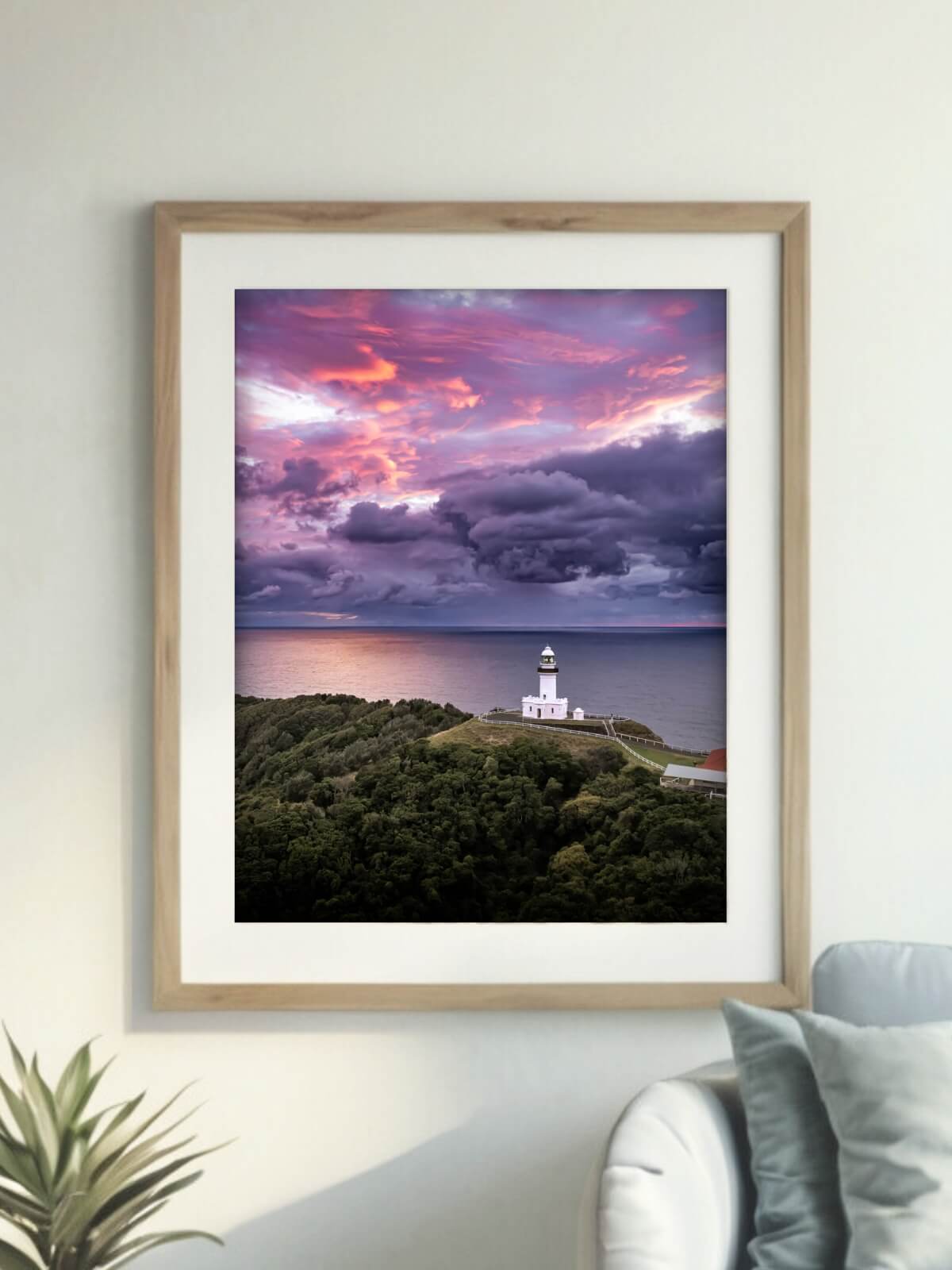 Framed Byron Bay lighthouse art print with vibrant sunrise displayed on a minimalistic wall in a cozy room.