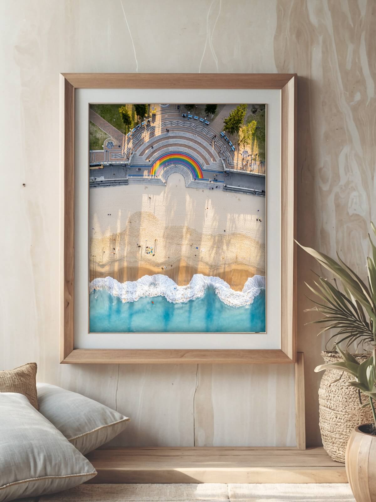 Framed print of Coogee Pavilion with rainbow steps displayed on a wall in a modern living room, featuring a hanging chair and coffee table.