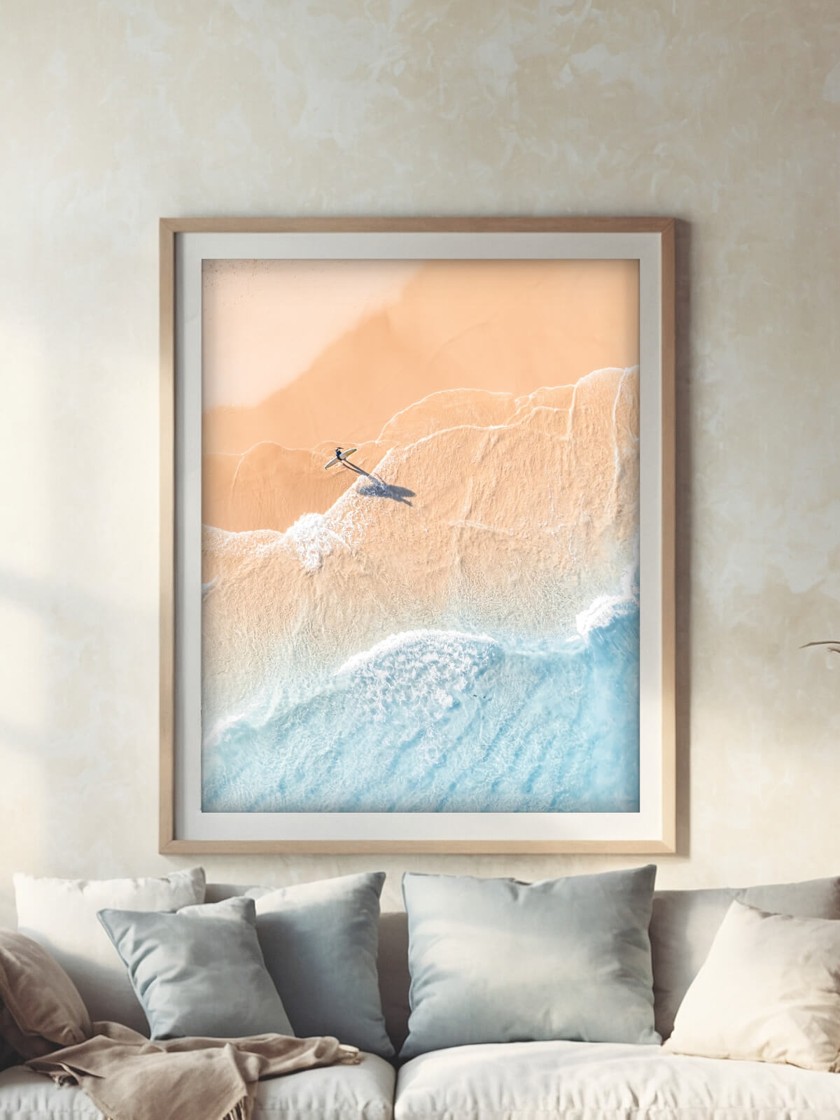 Aerial view of a lone surfer walking on sandy beach with gentle ocean waves at Byron Bay