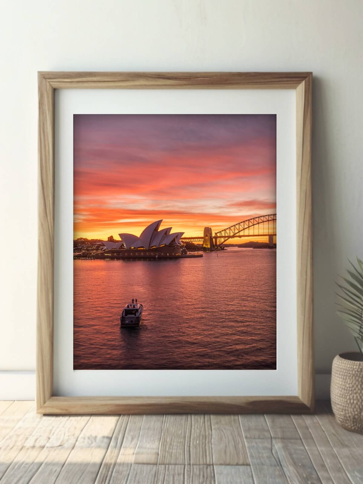 Framed photograph of Sydney Opera House and Harbour Bridge at sunset, with a yacht on the water, capturing a vibrant coastal scene.