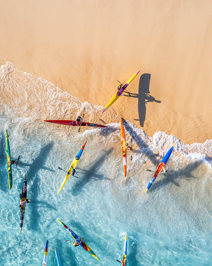 Colorful kayakers returning to Bondi Beach in Sydney, captured from above during a training session.