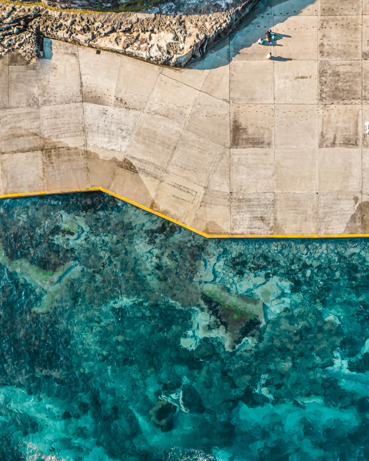 Top-down drone photo of Clovelly Beach’s concrete edges meeting clear turquoise waters in Sydney.