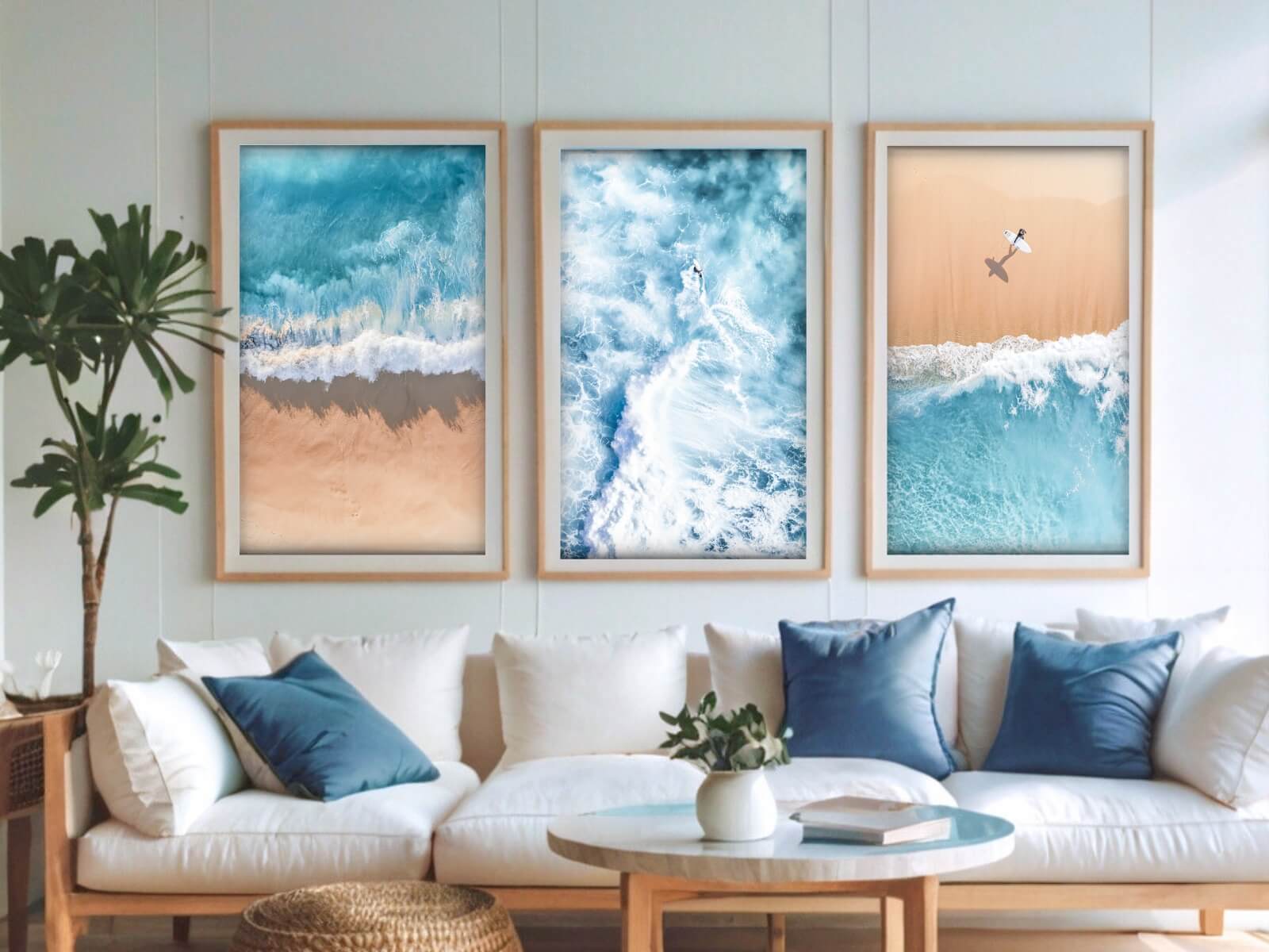 Three portrait frames of ocean and beach photos are displayed above a white and blue couch.