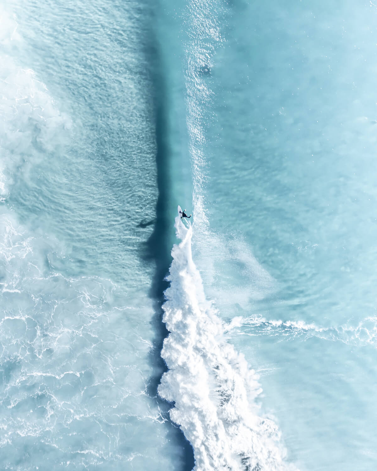 Aerial view of a surfer riding a wave in Byron Bay’s blue ocean