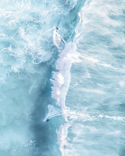 Aerial shot of surfers carving through turquoise waves at Bronte Beach, Sydney, showcasing the vibrant ocean colors and rhythmic wave patterns.