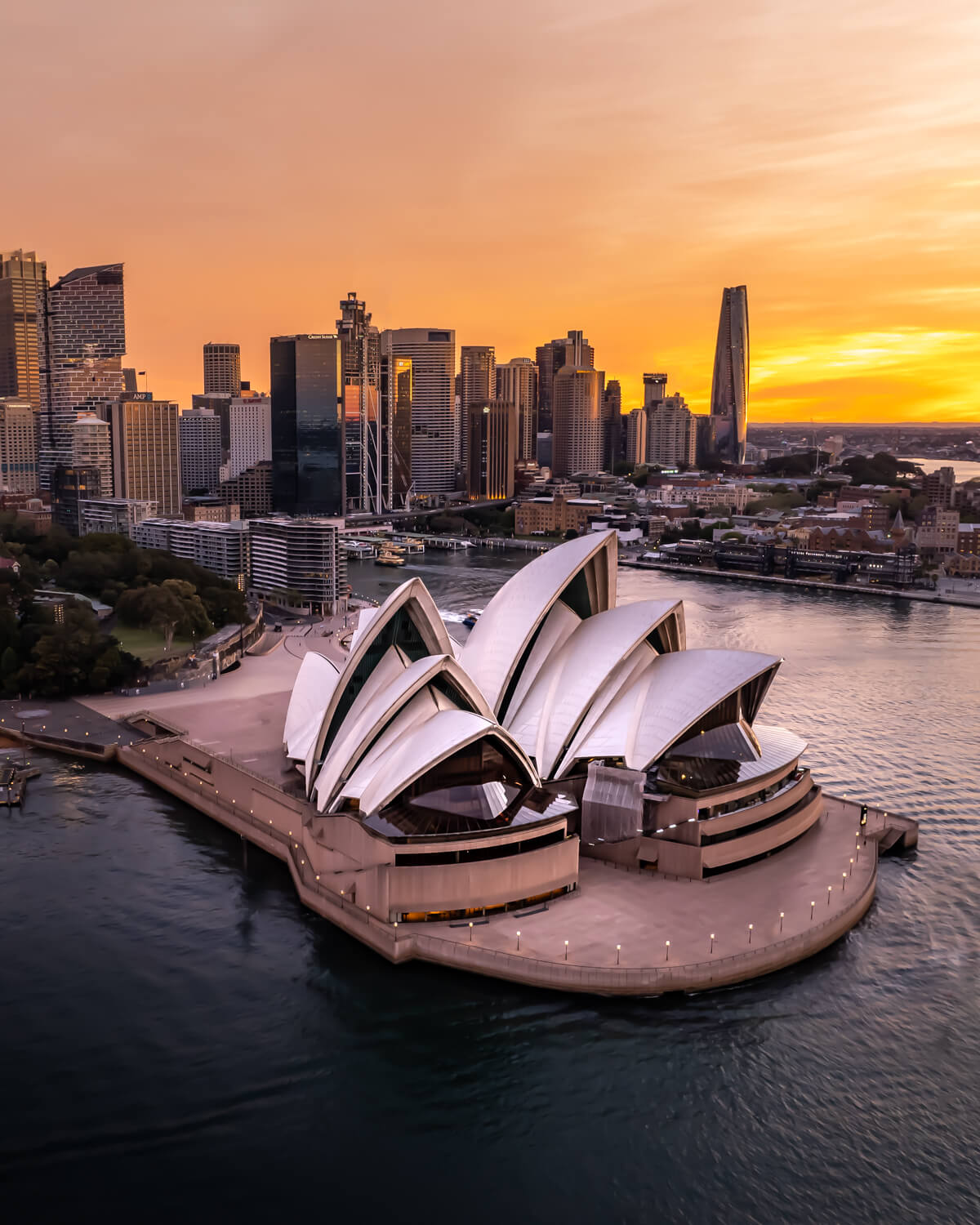 Sydney Opera House at sunset with city skyline in the background, captured during golden hour.