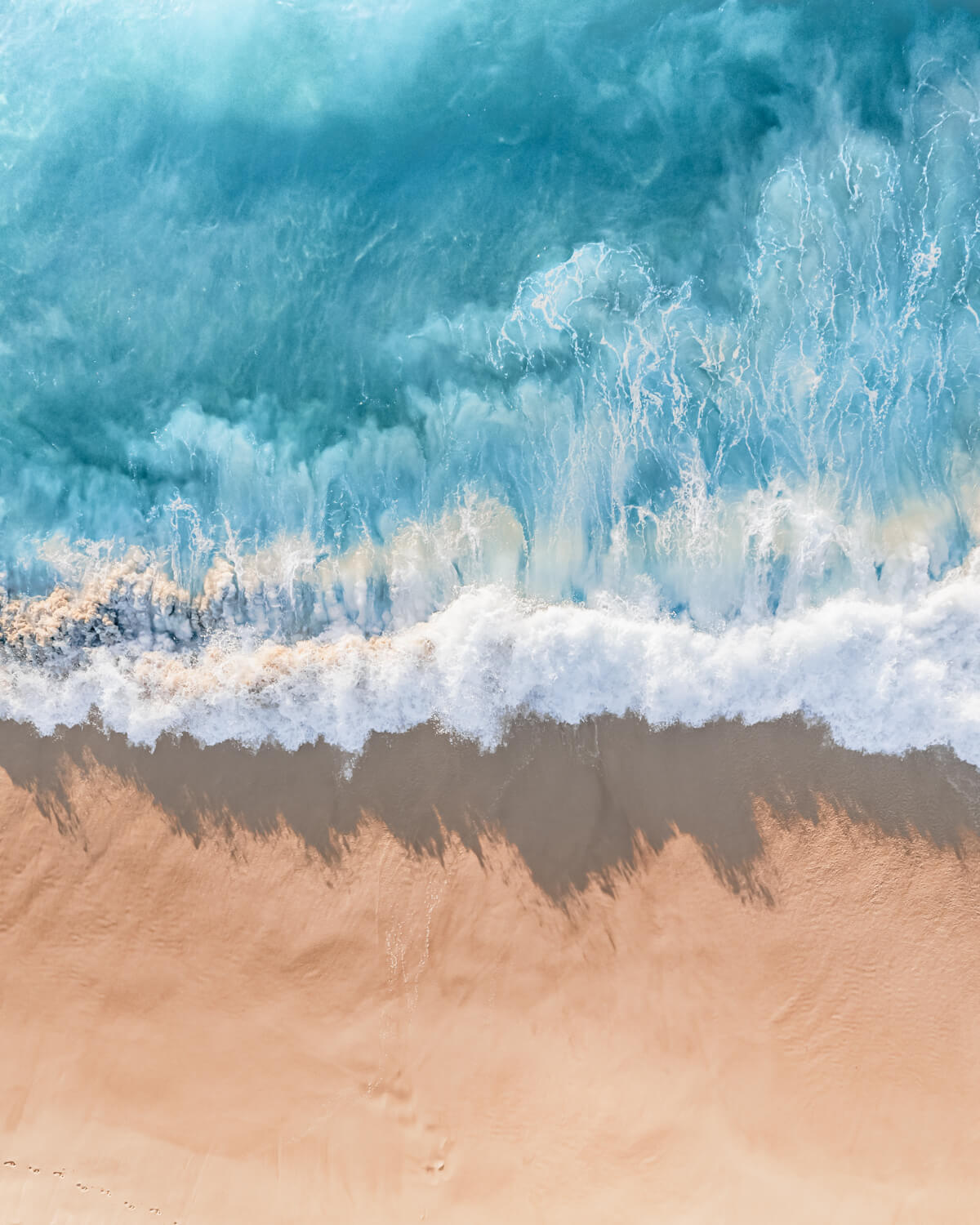 Turquoise ocean waves gently crashing onto a golden sandy shore