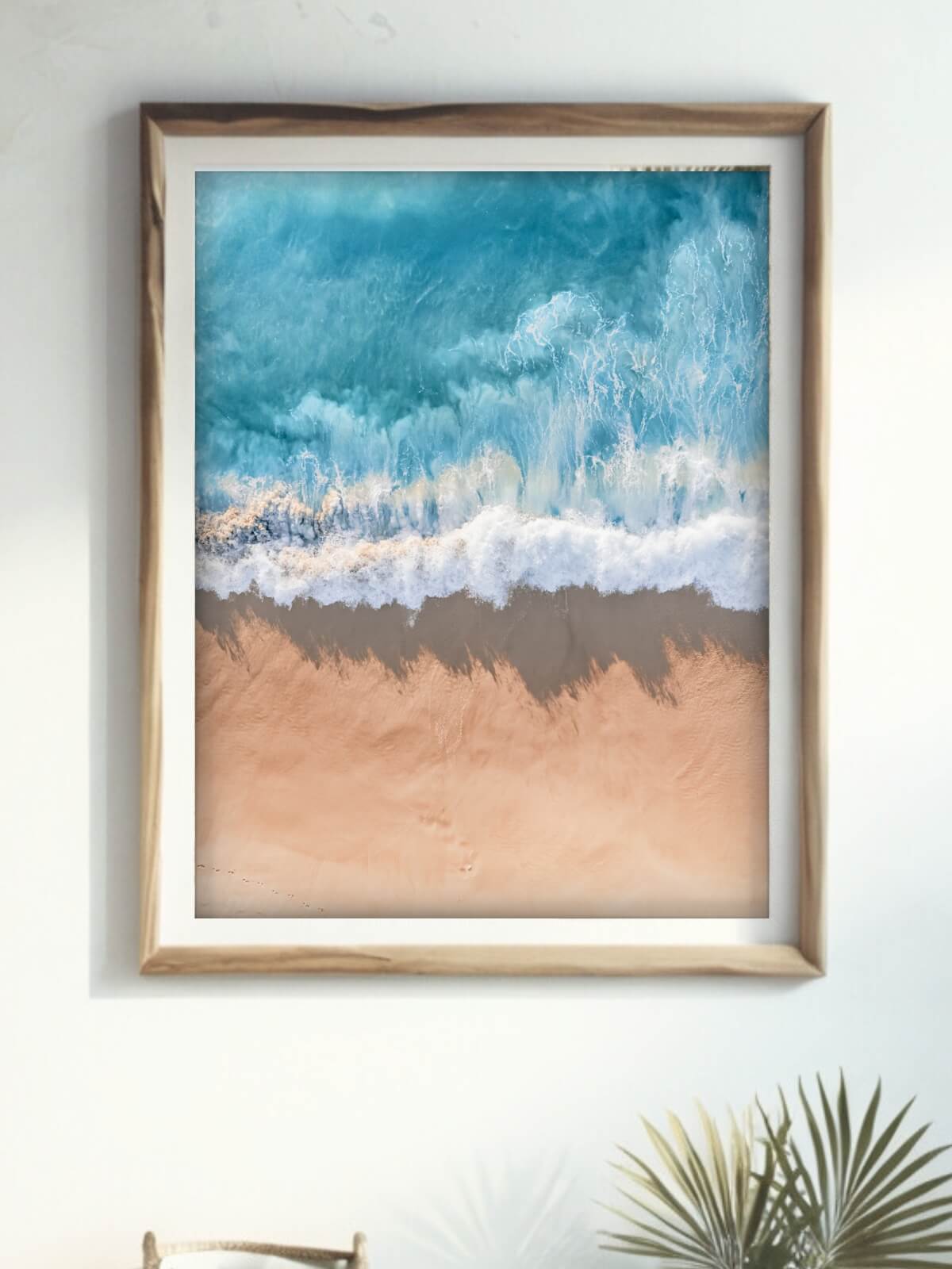 Framed coastal print of turquoise waves meeting sandy shore